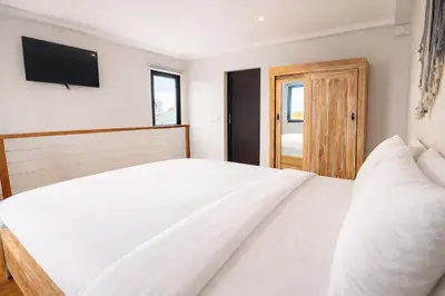 a bedroom with a white bed and a television at Glory Rentals in Kuta