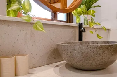 a sink in a bathroom with a faucet and plants at Green Mutiara Jimbaran in Jimbaran