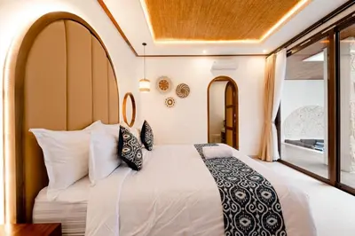a bedroom with a large white bed with pillows at Green Mutiara Jimbaran in Jimbaran