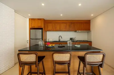 a kitchen with a black counter top and wooden cabinets at Villa Arta - A Calm, Tropical Villa in Umalas in Canggu