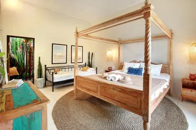a bedroom with a canopy bed and a living room at Seminyak Beach Seagrass Villa 4BR - pool & staff in Seminyak