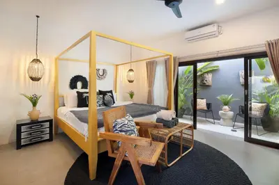 a bedroom with a canopy bed and a living room at Villa Suka Saki Seminyak with pool, wifi, & staff in Seminyak