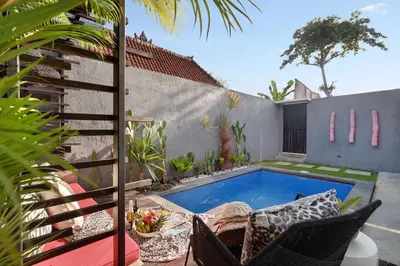 a backyard with a swimming pool and two chairs at Villa Suka Saki Seminyak with pool, wifi, & staff in Seminyak