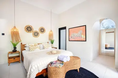 a bedroom with a bed and a wicker chair at Villa Sobramesa Seminyak with pool, butler & parking in Seminyak