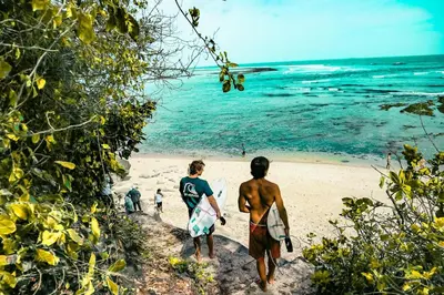 a group of people walking on the beach with surfboards at Villa Sobramesa Seminyak with pool, butler & parking in Seminyak
