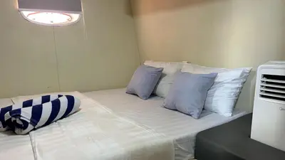 a bed with blue and white pillows in a room at La Merry Yacht cruise in Pulau Serangan