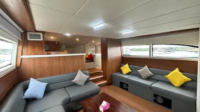 a living room with two blue couches and yellow pillows at La Merry Yacht cruise in Pulau Serangan