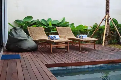 two chairs sitting on a deck next to a pool at Glenda Cozy 3 BR Private Pool Villa in Canggu