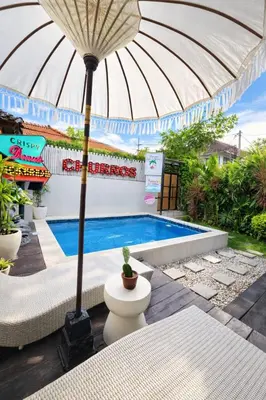 a patio with an umbrella and a swimming pool at 3BR Canggu Batu Belig Tropicana Villa - Walk to Beach in Canggu