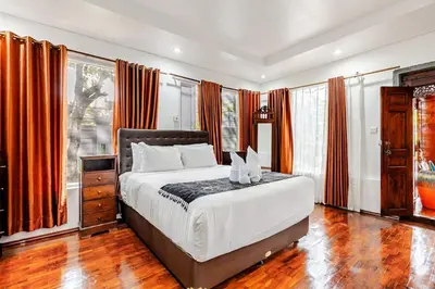 a bedroom with a large bed with orange curtains at iVAVev Isus Lucersfera in Seminyak