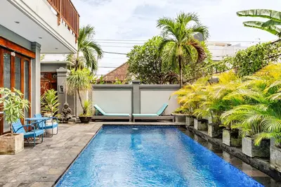 a pool in a backyard with chairs and palm trees at iVAVev Isus Lucersfera in Seminyak