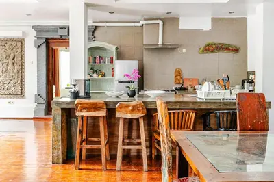 a kitchen with a large wooden island with chairs at iVAVev Isus Lucersfera in Seminyak