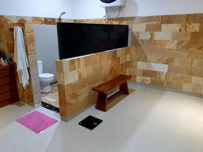 a bathroom with a wall with a tv and a bench at Elegant oasis between Canggu and Seminyak in Kerobokan