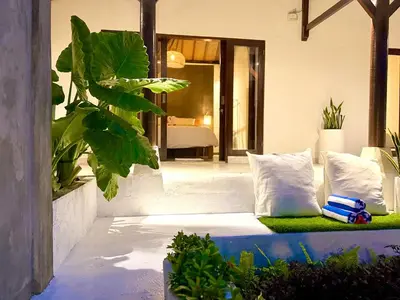 a bedroom with a bed with pillows and plants at Nauu Villa Umalas in Kerobokan