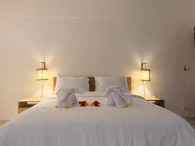two stuffed animals on a white bed with two lamps at Nauu Villa Umalas in Kerobokan