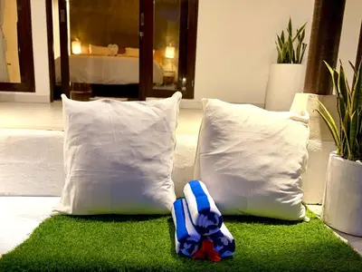 a pair of flip flops sitting on a green rug next to pillows at Nauu Villa Umalas in Kerobokan
