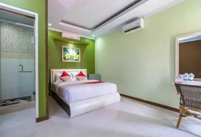 a bedroom with green walls and a bed with red pillows at DBI Hotel - 1 minute to the Beach and 1 second to the Mall in Ngurah Rai International Airport