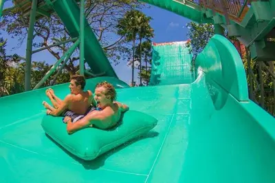 two boys riding on a water slide at a water park at DBI Hotel - 1 minute to the Beach and 1 second to the Mall in Ngurah Rai International Airport