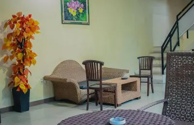 a room with chairs and a table and stairs at DBI Hotel - 1 minute to the Beach and 1 second to the Mall in Ngurah Rai International Airport