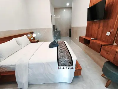 a bedroom with a bed with a television and a chair at Jepun segara homestay in Ngurah Rai International Airport