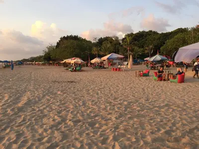 a beach with umbrellas and people sitting on the sand at Villa Tentrem Legian in Legian