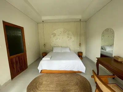 a bedroom with a large white bed and a piano at Villa Makna Canggu in Canggu