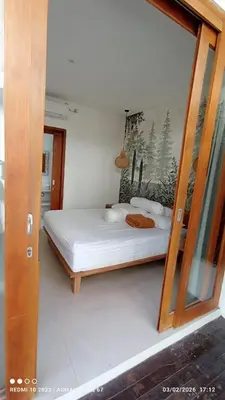 a bedroom with a white bed with a picture on the wall at Palm Harmony Villa's Seminyak in Seminyak
