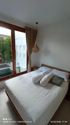 a bedroom with a bed with pillows and a window at Palm Harmony Villa's Seminyak in Seminyak