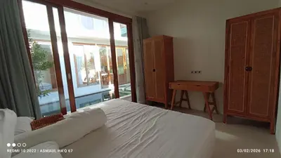 a bedroom with a white bed and a large window at Palm Harmony Villa's Seminyak in Seminyak