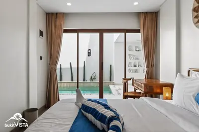 a bedroom with a bed and a desk and a window at Hummingbird Villa by Bukit Vista in Kerobokan