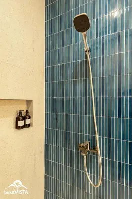 a shower in a bathroom with a blue tile wall at Hummingbird Villa by Bukit Vista in Kerobokan