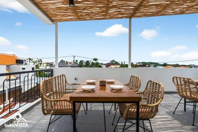 a wooden table and chairs on a balcony at Hummingbird Villa by Bukit Vista in Kerobokan