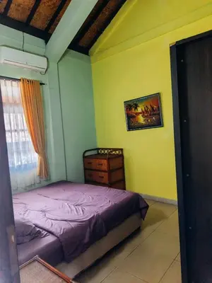 a bedroom with a purple bed and a dresser at Widi House in Nusa Dua