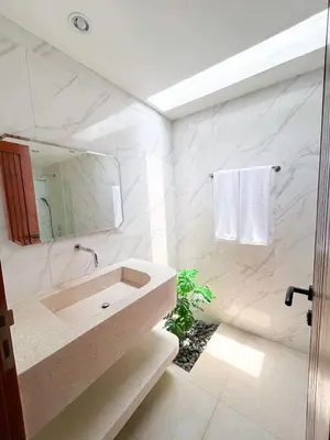 a white bathroom with a sink and a mirror at Ratu Guest House in Mantaak