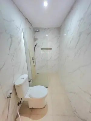 a white bathroom with a toilet and a shower at Ratu Guest House in Mantaak
