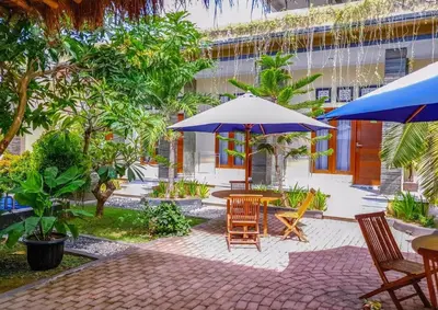 a patio with tables and chairs and umbrellas at Ratu Guest House in Mantaak