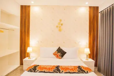 a bedroom with a large bed with two lamps at Ratu Guest House in Mantaak
