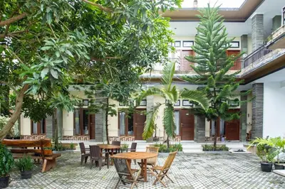 a courtyard with tables and chairs and trees at Ratu Guest House in Mantaak
