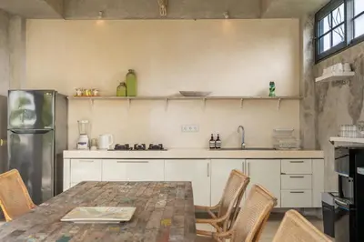 a kitchen with a table and chairs and a refrigerator at Duur Apartment by Betterplace in Seminyak