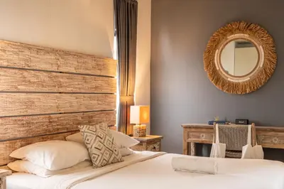 a bedroom with a bed with a wooden headboard and a mirror at Duur Apartment by Betterplace in Seminyak