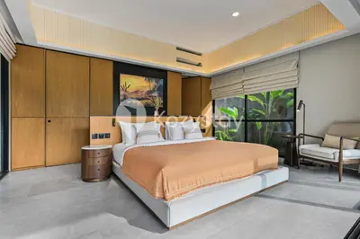 a bedroom with a king sized bed and a chair at Niskala Villa by Kozystay - Natadesa Resort in Jimbaran