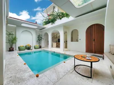 an indoor swimming pool with a table in a house at Villa Emilia Canggu by Nagisa Bali in Canggu