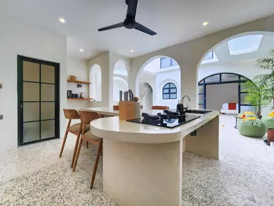 a kitchen with an island in a room with windows at Villa Emilia Canggu by Nagisa Bali in Canggu