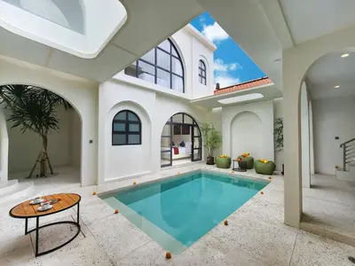 an indoor swimming pool in a house with a vaulted ceiling at Villa Emilia Canggu by Nagisa Bali in Canggu