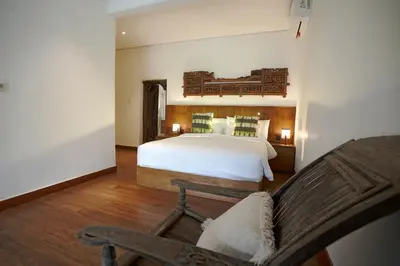 a bedroom with a large white bed and a chair at Juan Villa Legian in Seminyak
