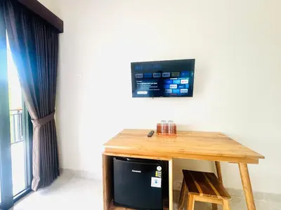 a wooden table with a television on a wall at Umah Kak Pasek in Jimbaran