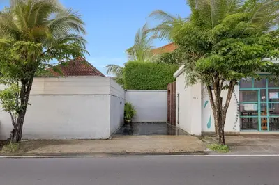 a white building with palm trees next to a street at 6BR Seminyak Oasis with 2 Private Pools in Seminyak