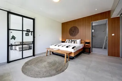 a bedroom with a bed and a wooden wall at 6BR Seminyak Oasis with 2 Private Pools in Seminyak