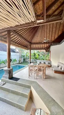 a pavilion with a table and chairs and a pool at Authentic Balinese Riverside Villa in Kerobokan