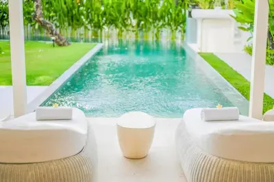 a swimming pool with two white chairs next to a pool at Yahira Stunning Garden 5 BR Private Pool Villa in Canggu